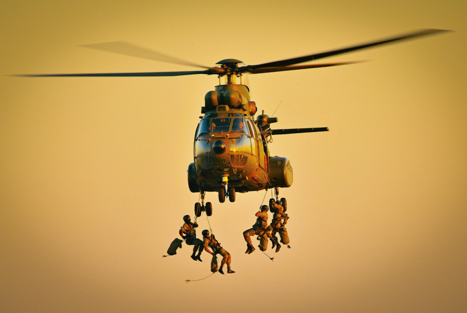 Military operators descending from a helicopter